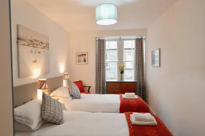a bedroom with two beds and a window at Providence Cottage in Kirkcudbright