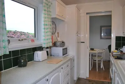 a kitchen with a counter with a microwave and a window at 31 Laigh Isle in Isle of Whithorn