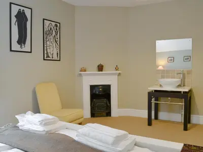 a room with a fireplace and a chair and a sink at Trevene in Buttermere