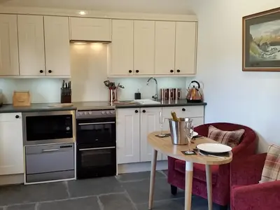 a kitchen with white cabinets and a wooden table at Field House Bothy - Uk12571 in Borrowdale Valley