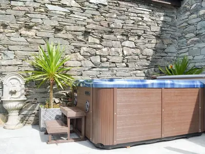 a hot tub in a patio with a stone wall at Field House Cottage - Uk12573 in Borrowdale Valley