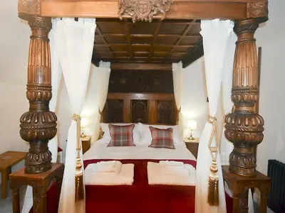 a bedroom with a canopy bed with wooden posts at Field House Cottage - Uk12573 in Borrowdale Valley