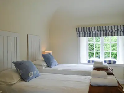 two beds in a room with a window at Orchard Cottage - Uk12525 in Garlieston