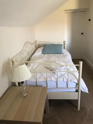 a bedroom with a bed with a lamp and a table at Laundry Cottage in Dumfries