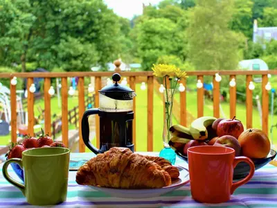 a table with a plate of food and coffee cups at Curlew Cottage in Creetown