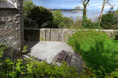 a wooden bench sitting in front of a stone wall at Tower Lodge in Auchencairn