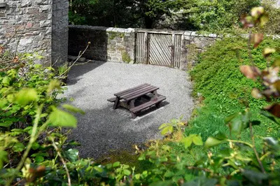 a wooden bench sitting in the middle of a garden at Tower Lodge in Auchencairn