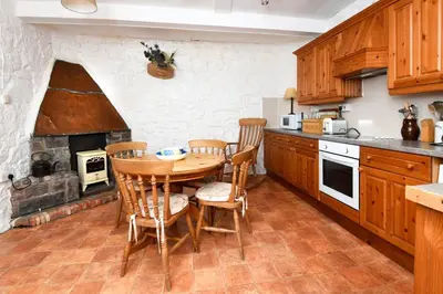 a kitchen with a wooden table and a fireplace at Tower Lodge in Auchencairn