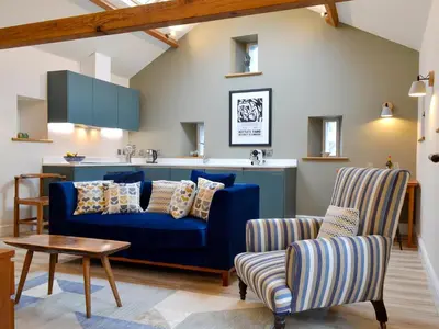 a living room with a blue couch and two chairs at The Hayloft in Caldbeck