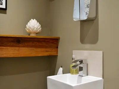 a bathroom with a white sink and a wooden shelf at The Hayloft in Caldbeck