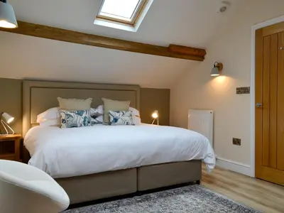 a bedroom with a large white bed with a window at The Hayloft in Caldbeck