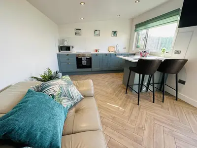 a living room with a couch and a kitchen at Hazells Lodge Farm Stay Sleeps 2 Undercover Hottub and Pool Table in Galston