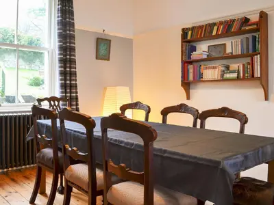 a dining room table with chairs and a book shelf at Kingswood in Whitehaven