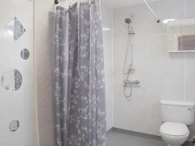 a bathroom with a shower curtain and a toilet at Ardlochan Cottage in Maidens