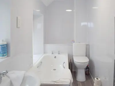 a white bathroom with a tub and a toilet at Ardlochan Cottage in Maidens