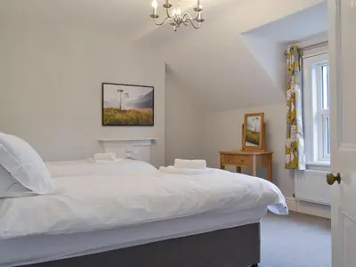 a bedroom with a white bed and a chandelier at The Birches in Keswick
