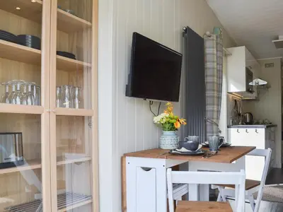 a dining room with a table with a television on a wall at Lapwing in Westward