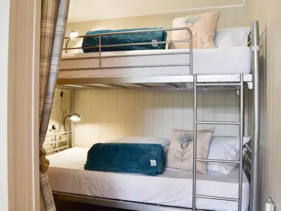 a room with three bunk beds with white sheets at Lapwing in Westward