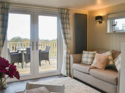 a living room with a couch and a sliding glass door at Merlin's Cabin in Westward