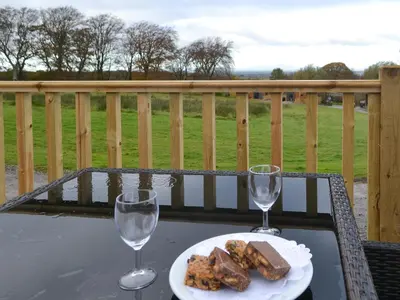 a table with a plate of food and two wine glasses at Merlin's Cabin in Westward