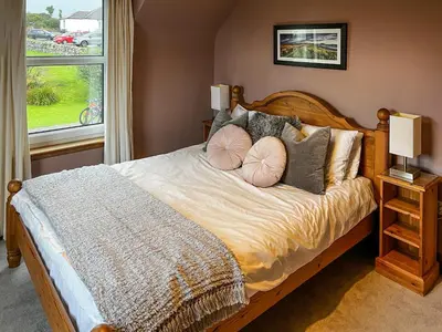 a bedroom with a bed with pillows and a window at Saffron in Portpatrick
