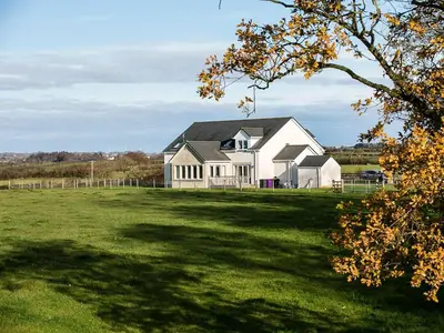 a large white house on a large grass field at Wheatfield House in Kilmaurs
