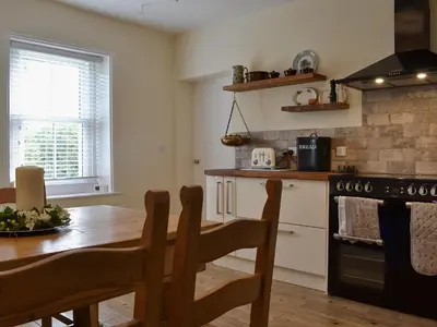 a kitchen with a wooden table and a table and a stove at Blaithwaite Cottage in Blencogo