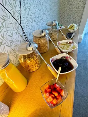a wooden table with bowls of fruit and jars of food at Rockhill Guest House in Moffat
