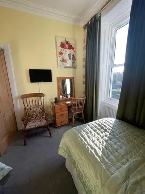 a bedroom with a bed and a desk and a window at Rockhill Guest House in Moffat