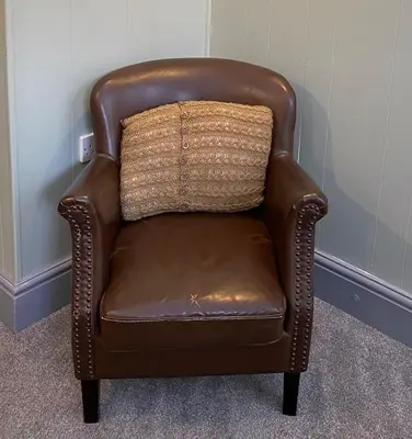 a brown chair with a pillow on top of it at Rose Cottage in Wigton