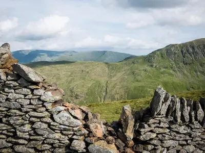 a stone wall with mountains in the background at YHA Helvellyn in Glenridding