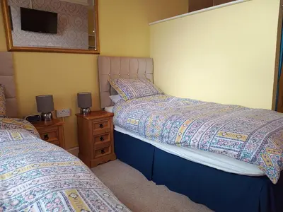 a bedroom with two beds and a tv on a night stand at Green View Guest House in Silloth