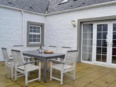 a table and chairs sitting on a patio at Torcross Barn in Tarbolton