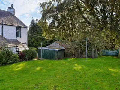 a yard with a fence and a house at Butterhole Farmhouse in Kelton