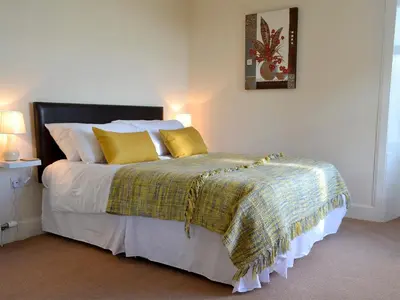 a bedroom with a large bed with yellow pillows at Butterhole Farmhouse in Kelton