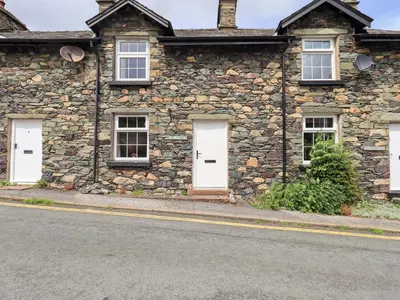 an old stone house with white doors on a street at Millcroft in Penrith