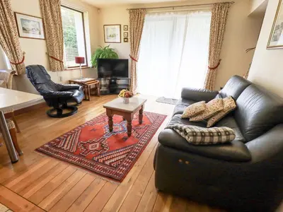 a living room with a black leather couch and a table at Stonegarth Cottage in Ambleside