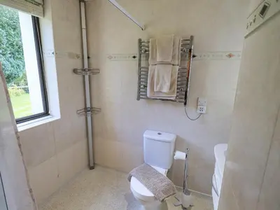 a bathroom with a toilet and a shower with towels at Stonegarth Cottage in Ambleside