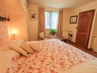 a bedroom with a large bed with a floral bedspread at Stonegarth Cottage in Ambleside