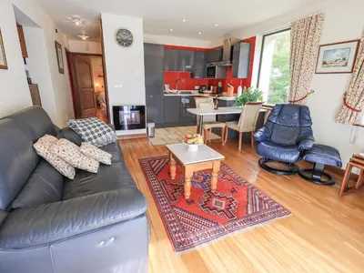 a living room with a black leather couch and a table at Stonegarth Cottage in Ambleside
