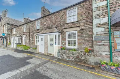 a brick building with white doors on a street at Poppy's Cottage in Ambleside