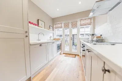 a kitchen with white cabinets and white counter tops at Poppy's Cottage in Ambleside