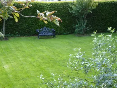 a black bench sitting in a grass yard at Somerton House Hotel in Lockerbie