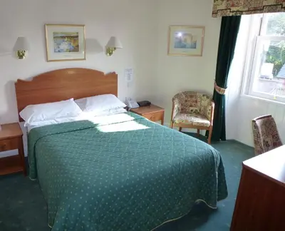 a bedroom with a bed with a green comforter at Somerton House Hotel in Lockerbie