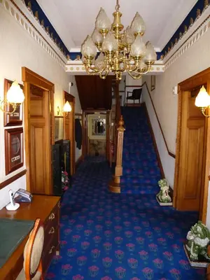 a hallway with a blue carpet and a chandelier at Somerton House Hotel in Lockerbie