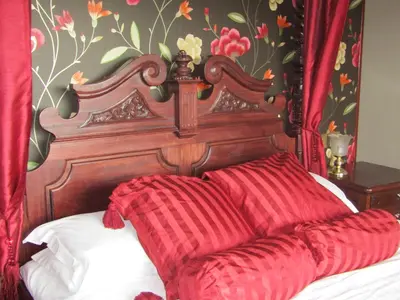 a bed with a wooden head board with red pillows at Hunters Lodge Hotel in Gretna Green