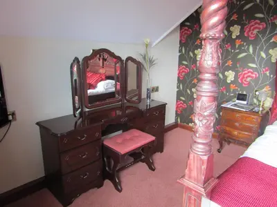 a bedroom with a dresser and a mirror and a bed at Hunters Lodge Hotel in Gretna Green