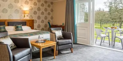 a hotel room with a bed and a table and chairs at Cally Palace Hotel & Golf Course in Gatehouse of Fleet