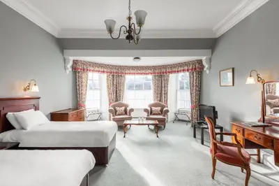 a hotel room with two beds and a desk at Cally Palace Hotel & Golf Course in Gatehouse of Fleet