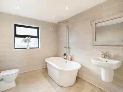 a bathroom with a tub and a sink and a toilet at North Plain Barn in Bowness-on-Solway